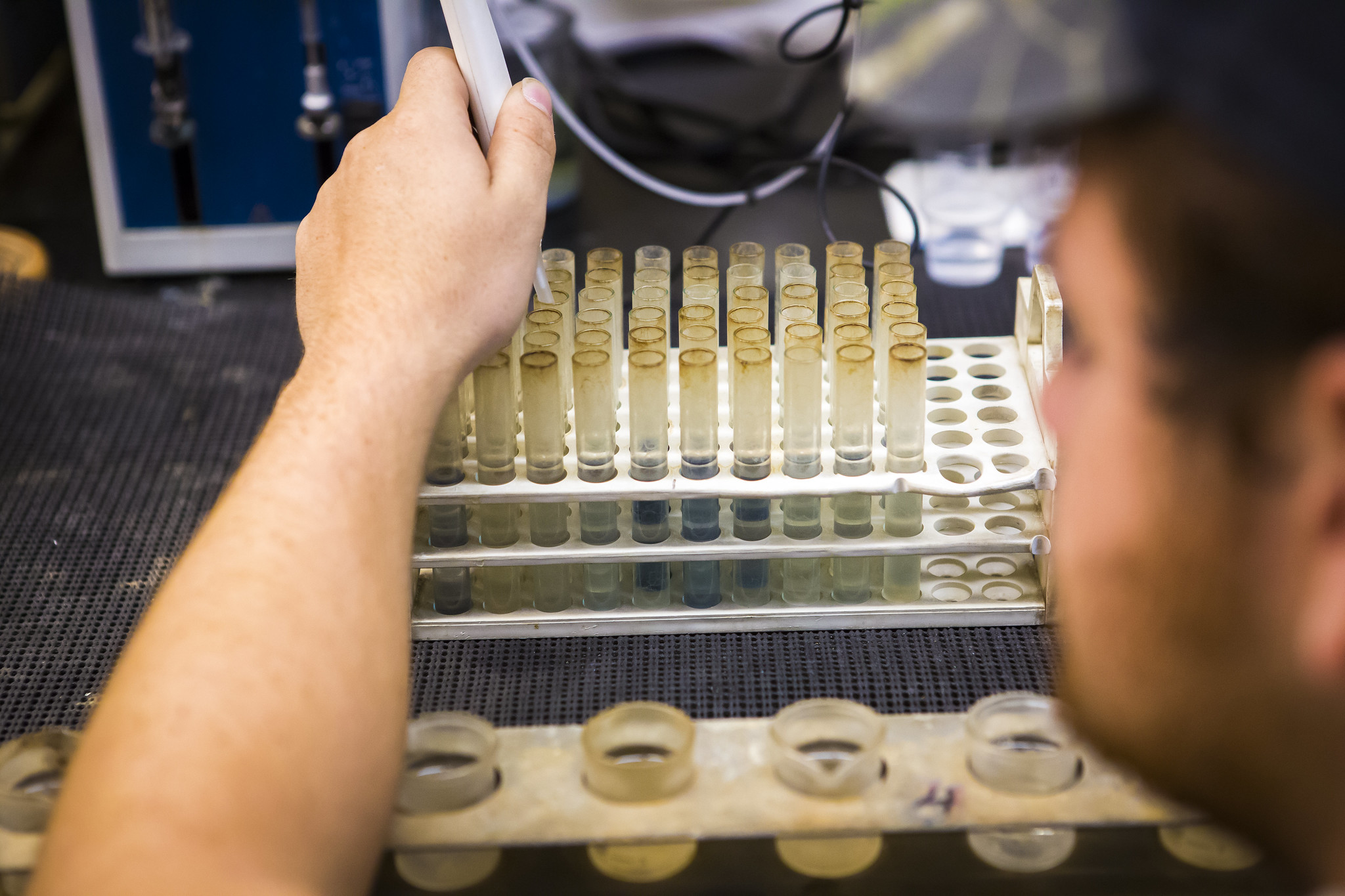 Image of a scientist filling clear tubes with soil to be tested.