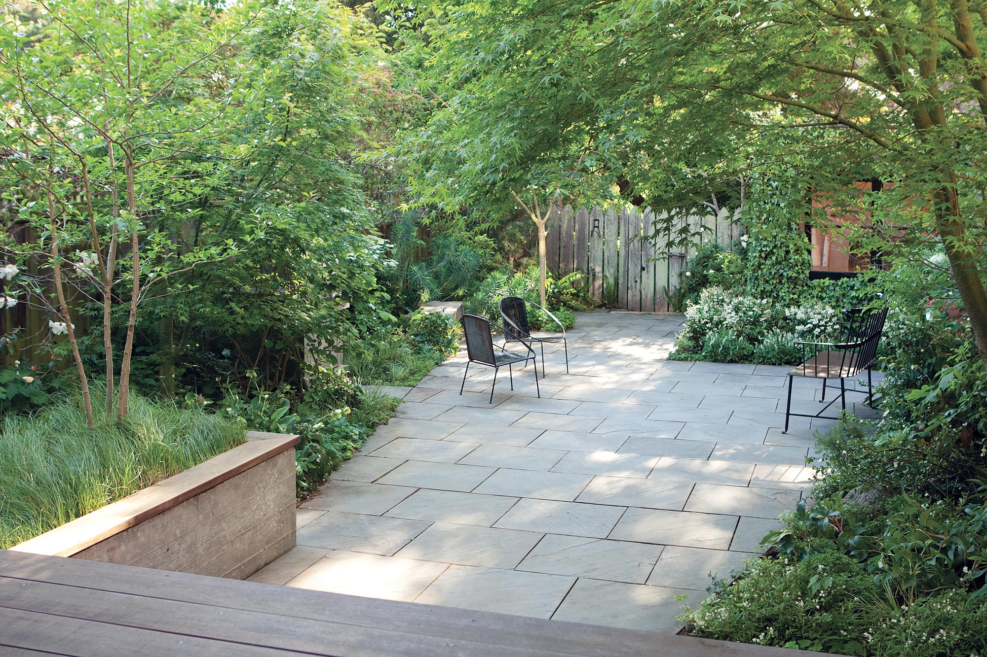 Bluestone patio with dimensionally cut stone bordered by a lush vegetation and garden.
