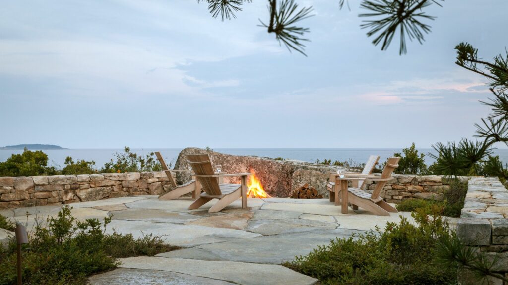 Flagstone patio with a natural wood burning firepit bordered by natural boulders.