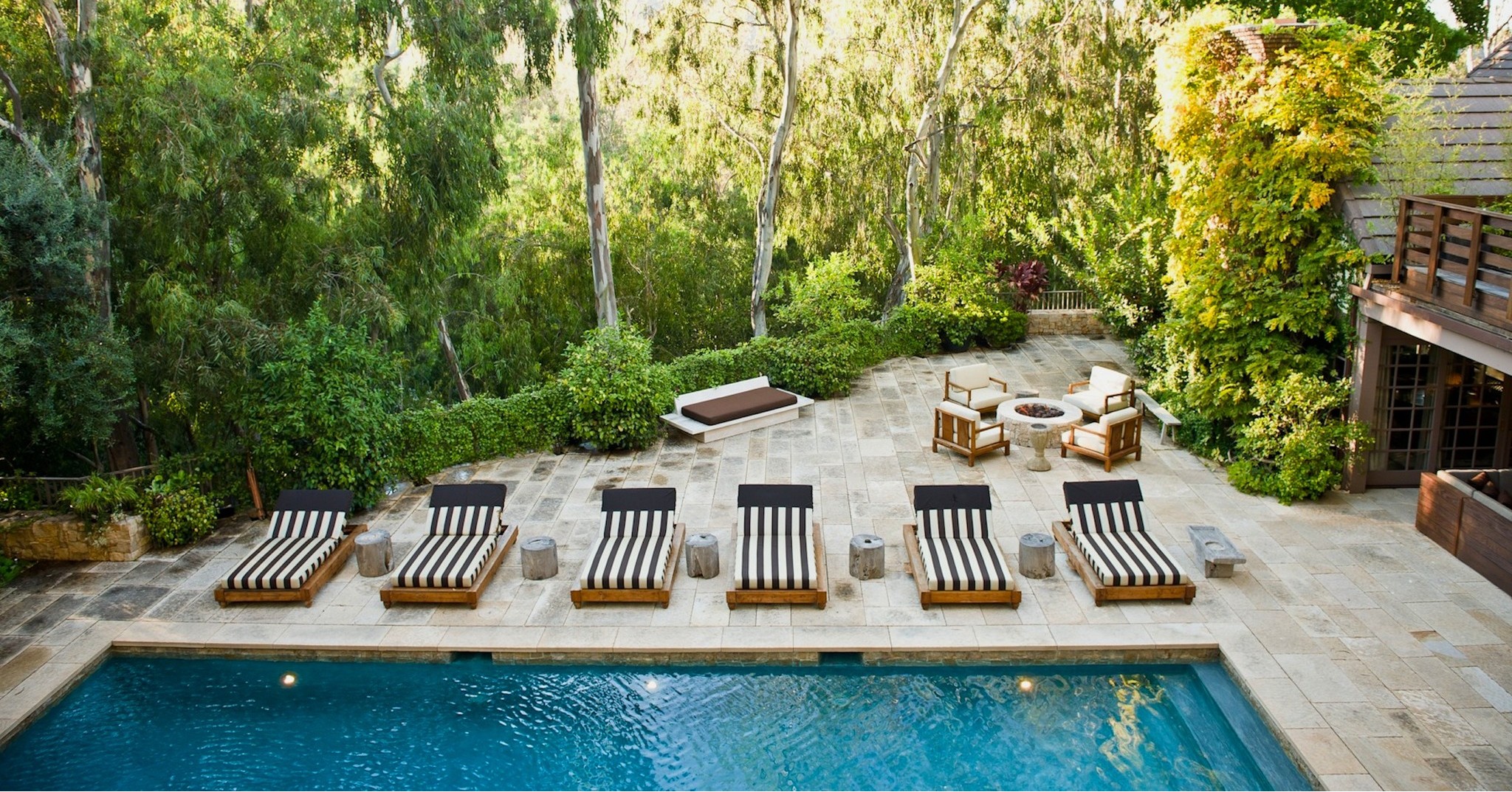 Project by Mark Tessier Landscape Architecture of a Backyard Wet Laid Patio with a Swimming Pool and Loungers in a Dense Woodland