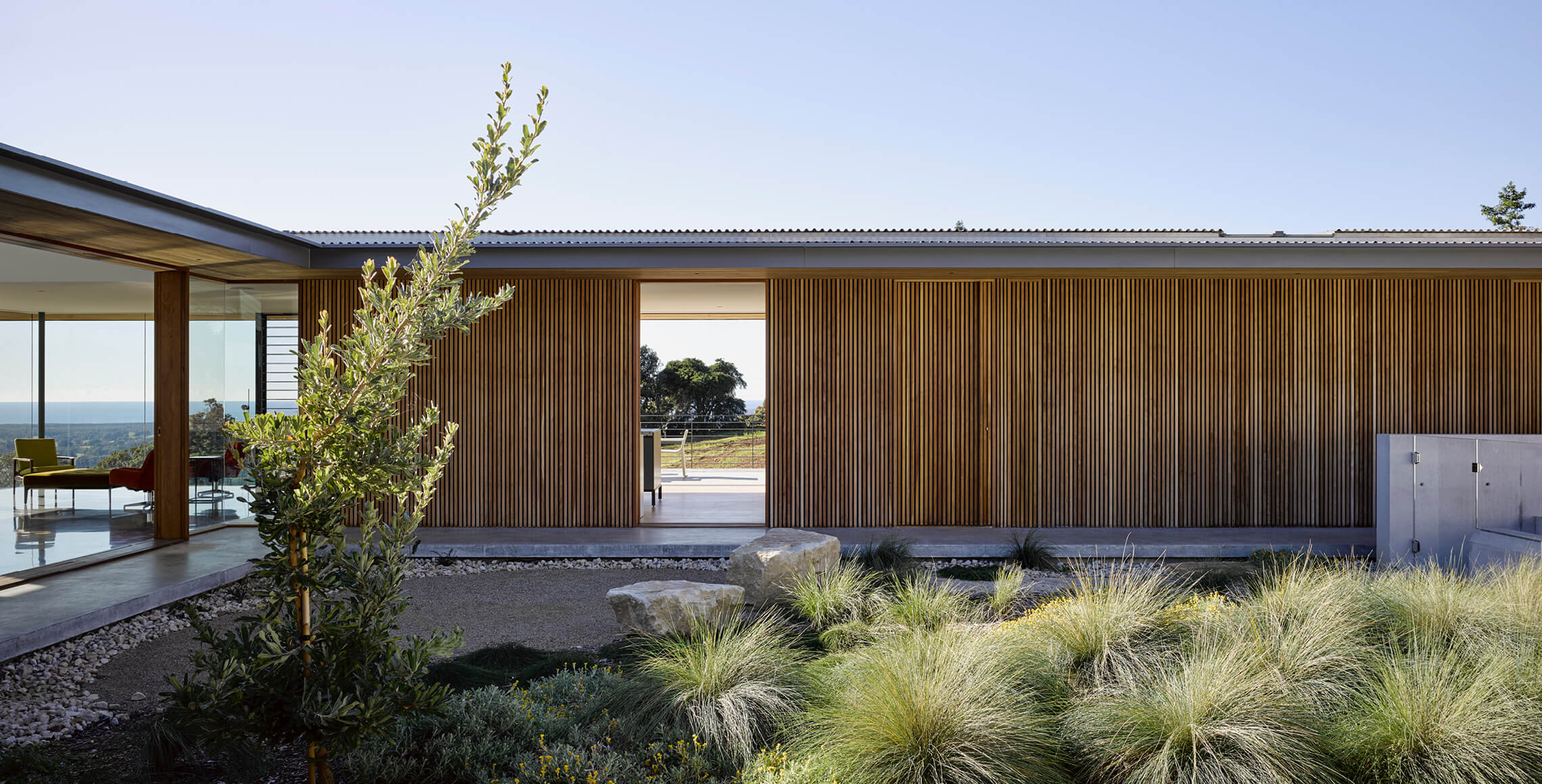 Natural boulders and ornamental grasses create the landscape against the warmth of the wood on the house.