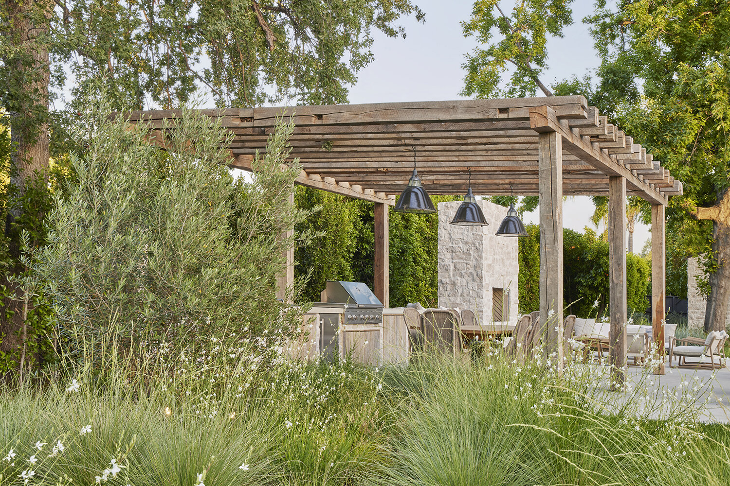 GSLA Studio and Amber Lewis create an outdoor kitchen area with grill and table for seating.